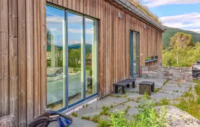 a building with glass windows and a bench outside at 2 Bedroom Cozy Home In Edland in Vågsli