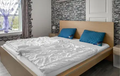 a bedroom with a large bed with two blue pillows at Pet Friendly Apartment In Harøy in Steinshamn