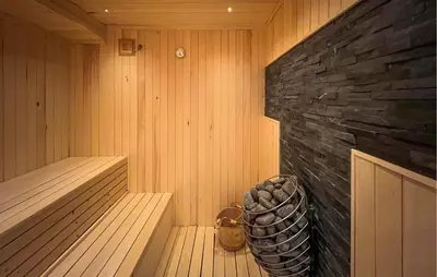 a sauna with a stone wall and a wooden tub at Lovely Home In Aurdal With Sauna in Aurdal