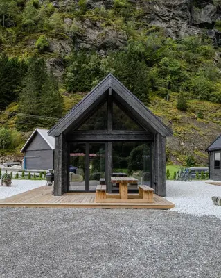 a pavilion with a table and benches in front of a mountain at Flåm Minisuite in Aurland