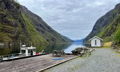 a dock with a picnic table and a boat on a lake at Hylen in Kvilldal