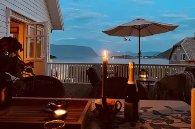 a table with two bottles of wine and an umbrella at Cozy house with sea view close to Ålesund in Havsteinen