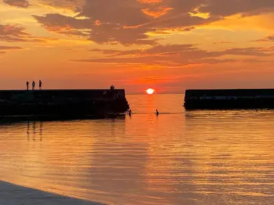 a sunset over the water with people on a pier at Cozy house with sea view close to Ålesund in Havsteinen
