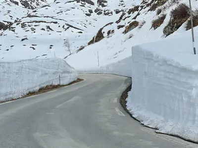 a road covered in snow next to a mountain at Over the Fjord in Leikanger