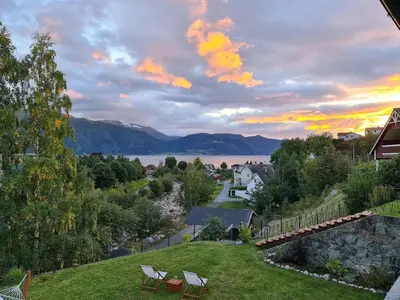 a view of a lake with two chairs on a lawn at Over the Fjord in Leikanger