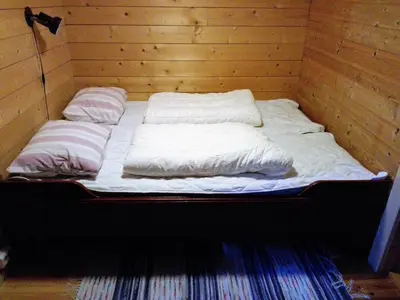 a bed in a wooden room with two pillows at Vårsetra in Bø
