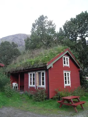 a red house with a grass roof with a picnic table at Vårsetra in Bø