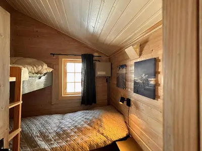 a bedroom in a log cabin with a bed and a window at A Peaceful Mountain Retreat in Beitostøl