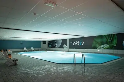 a large blue swimming pool in a building at Romslig leilighet med to soverom pluss hems med dobbeltseng in Bergen