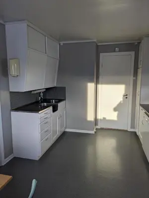 a kitchen with white cabinets and a sink and a door at Three bedroom home with an amazing mountain view! in Oppdal