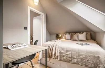 a attic bedroom with a bed and a table at Townhouse - 700 meters from Bryggen in Bergen