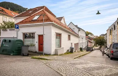 a white house with a red door on a street at Townhouse - 700 meters from Bryggen in Bergen