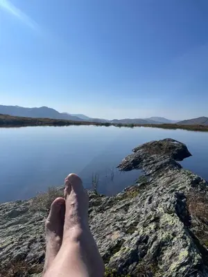 a persons feet on a rock near a body of water at Sognefjorden-Vik i Sogn in Brekka