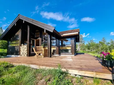 a cabin with a wooden deck in a field at Bright Cabin In Eggedals Beautiful Mountains in Eggedal