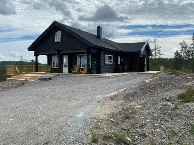 a black house with a porch and a driveway at Family Cabin At Blefjell in Lampeland