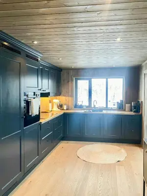 a large kitchen with blue cabinets and a table at Modern Cabin With Panoramic Views At Nesfjellet in Nesbyen