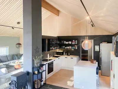 a kitchen with white cabinets and a living room at Sea Cabin With Views On Kallevikevegen in Mosterhamn