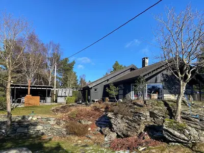 a large black building with a tree in front of it at Sea Cabin With Views On Kallevikevegen in Mosterhamn