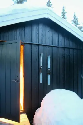 a black building with a snow pile in front of it at Charming Cabin In Vikerfjell in Hønefoss