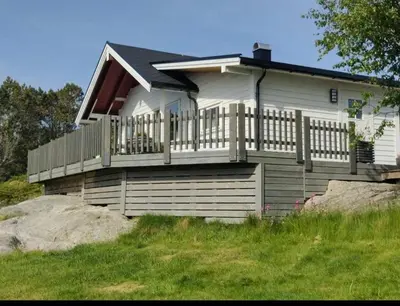 a white house with a porch and a fence at Færøya 49 in Nekkøyane