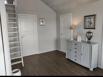 a room with a staircase and a dresser with a shelf at Færøya 49 in Nekkøyane