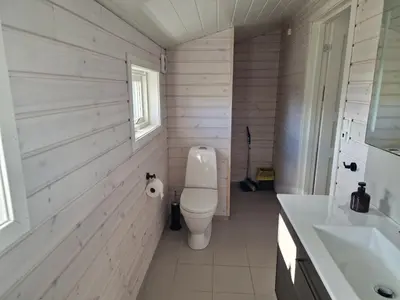 a white bathroom with a toilet and a sink at Færøya 49 in Nekkøyane