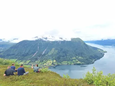 a group of people sitting on top of a hill at Villa ved sjøen og fjellene in Myklebostad