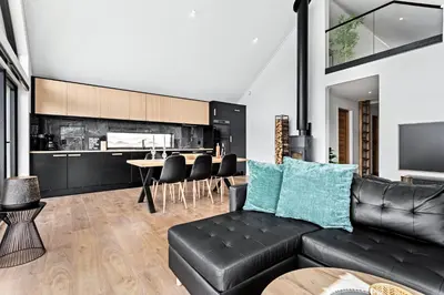 a living room with a black leather couch and a kitchen at Top-Floor Lakefront Apartment near Ski Resort in Hafslo