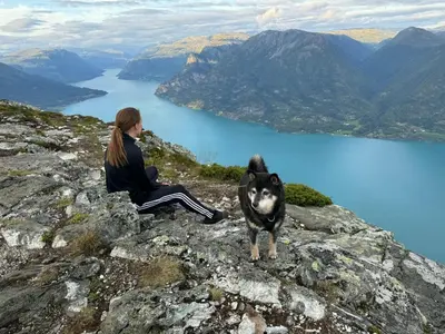 a woman and a dog sitting on top of a mountain at Top-Floor Lakefront Apartment near Ski Resort in Hafslo