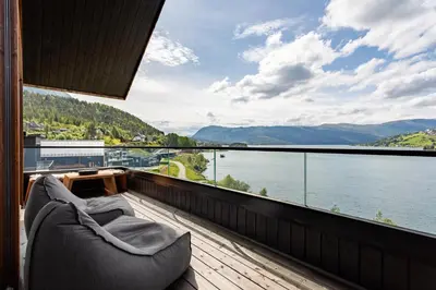 a balcony with a couch and a view of a lake at Top-Floor Lakefront Apartment near Ski Resort in Hafslo