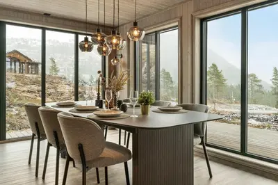 a dining room with a table and chairs and windows at Hydla Mountain Lodge in Stryn