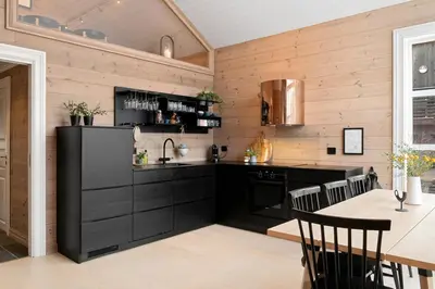 a kitchen with black cabinets and a table with chairs at Idyllic Apartment at Strandafjellet in Stranda