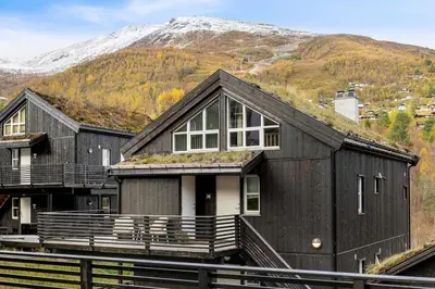 a black house with a mountain in the background at Idyllic Apartment at Strandafjellet in Stranda