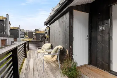 a wooden deck with a white door and chairs on it at Idyllic Apartment at Strandafjellet in Stranda