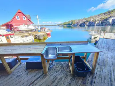 a wooden table on a dock with boats in the water at cozy house with boat dock, sauna - FJORDTID in Rubbestadneset