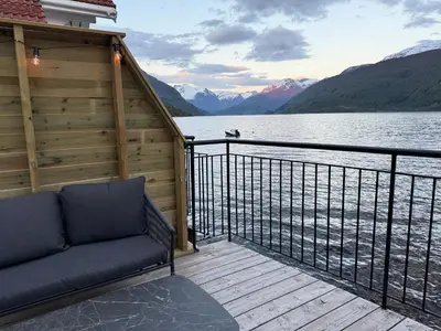 a balcony with a couch and a view of a lake at Stryn Fjord Cottage Faleide in Stryn