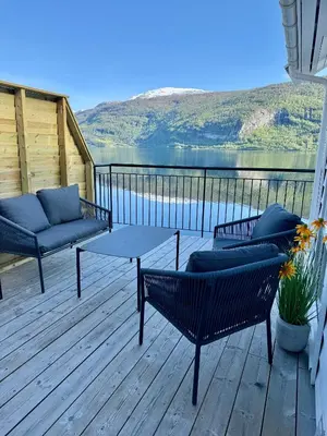 a deck with two couches and a table and chairs at Stryn Fjord Cottage Faleide in Stryn