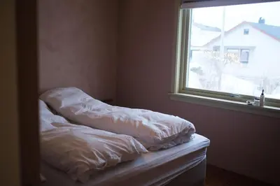 a bed with white sheets sitting next to a window at Nesheim in Alnes