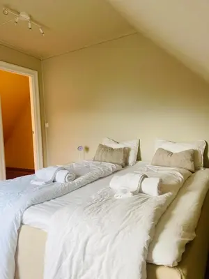 a large bed with white sheets and pillows on it at Skuteviken House in Bergen