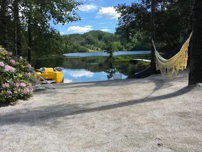 a hammock hanging from a tree next to a lake at #Beautiful outdoor area and cozy small cottage# in Fotlandsvåg