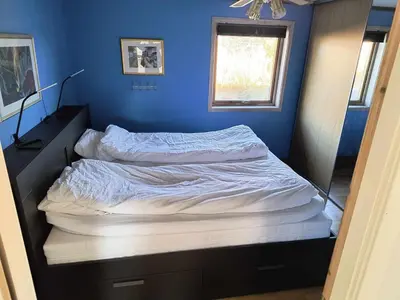 a bed in a bedroom with a blue wall at Skjærgårdsidyll in Askøy