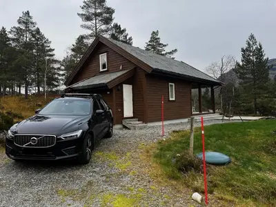 a car parked in front of a small house at Flott familiehytte på Haukås i Strandebarm in Kvam