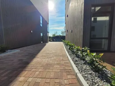 a brick walkway between two buildings next to a building at New apartment 5min to airport at Kokstad train station in Bergen