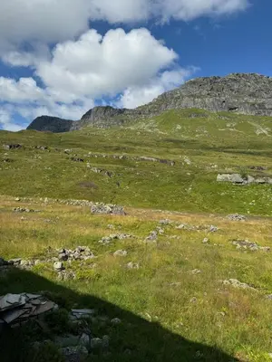 a field of grass with mountains in the background at Wild Norwegian nature, between Preikestolen & Trolltunga in Sauda