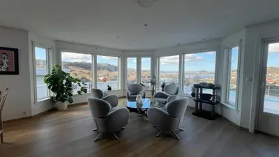 a living room with chairs and a table and windows at Villa with heated pool and magnificent view in Bergen