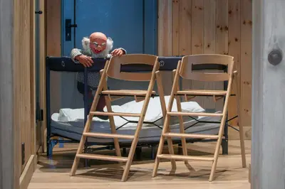 a person standing next to two wooden chairs at Nordic Gateway Logde in Hafjell