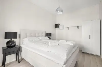 a white bedroom with a large bed with white sheets at Scandinavian Luxury in Bergen's Finest Street in Bergen