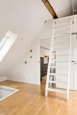 a white ladder in a white room with a staircase at Design Apartment by Bryggen - View & Location in Bergen