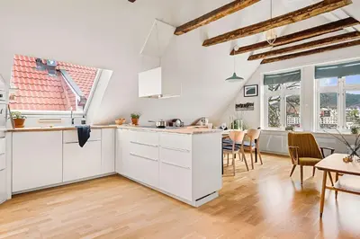 a kitchen with white cabinets and a dining room at Design Apartment by Bryggen - View & Location in Bergen