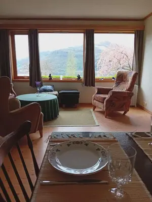 a living room with a table and a large window at Sandeidfjorden overnatting in Sandeid